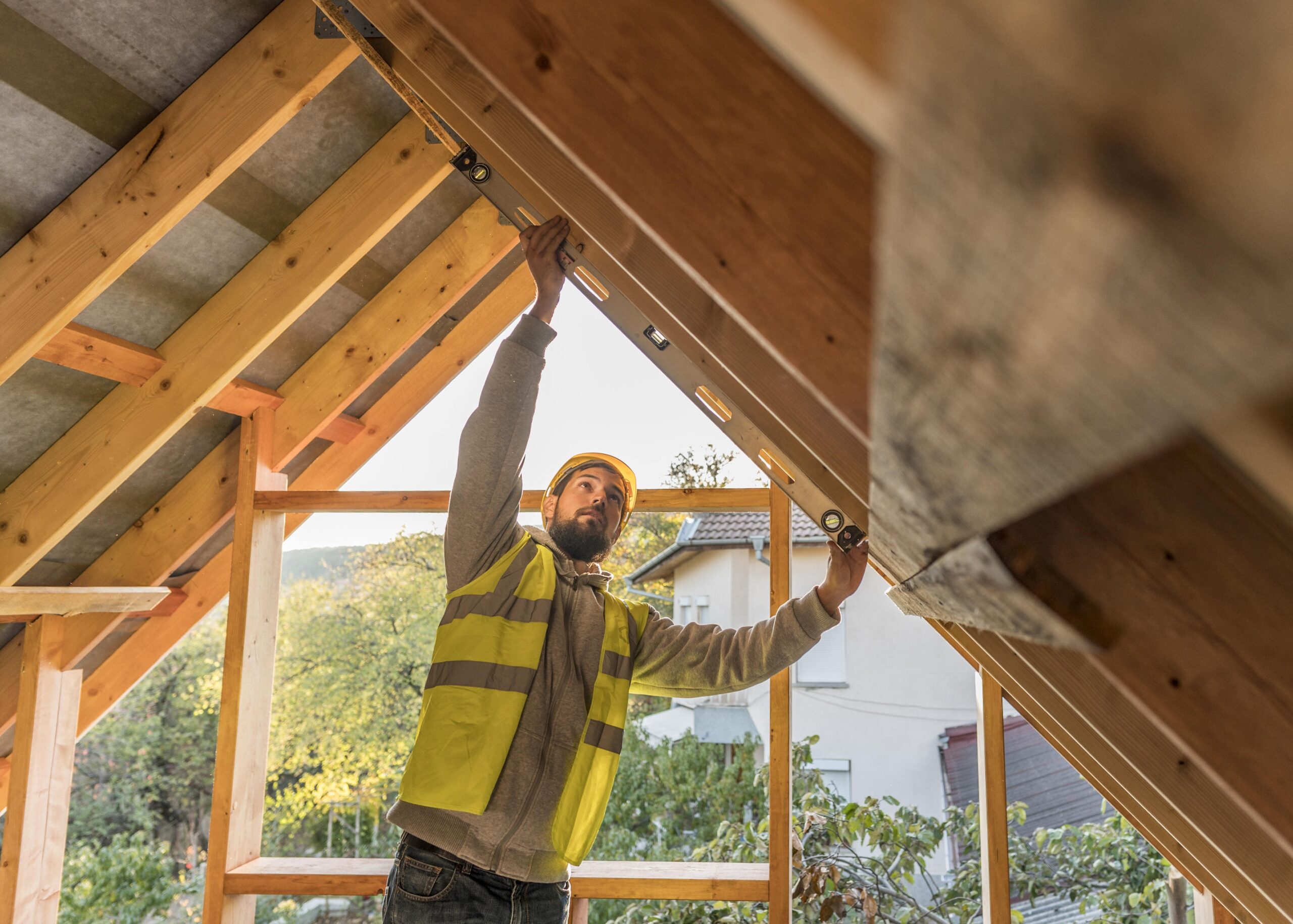 Carpenter man in yellow safety vest works on roof of a residential home