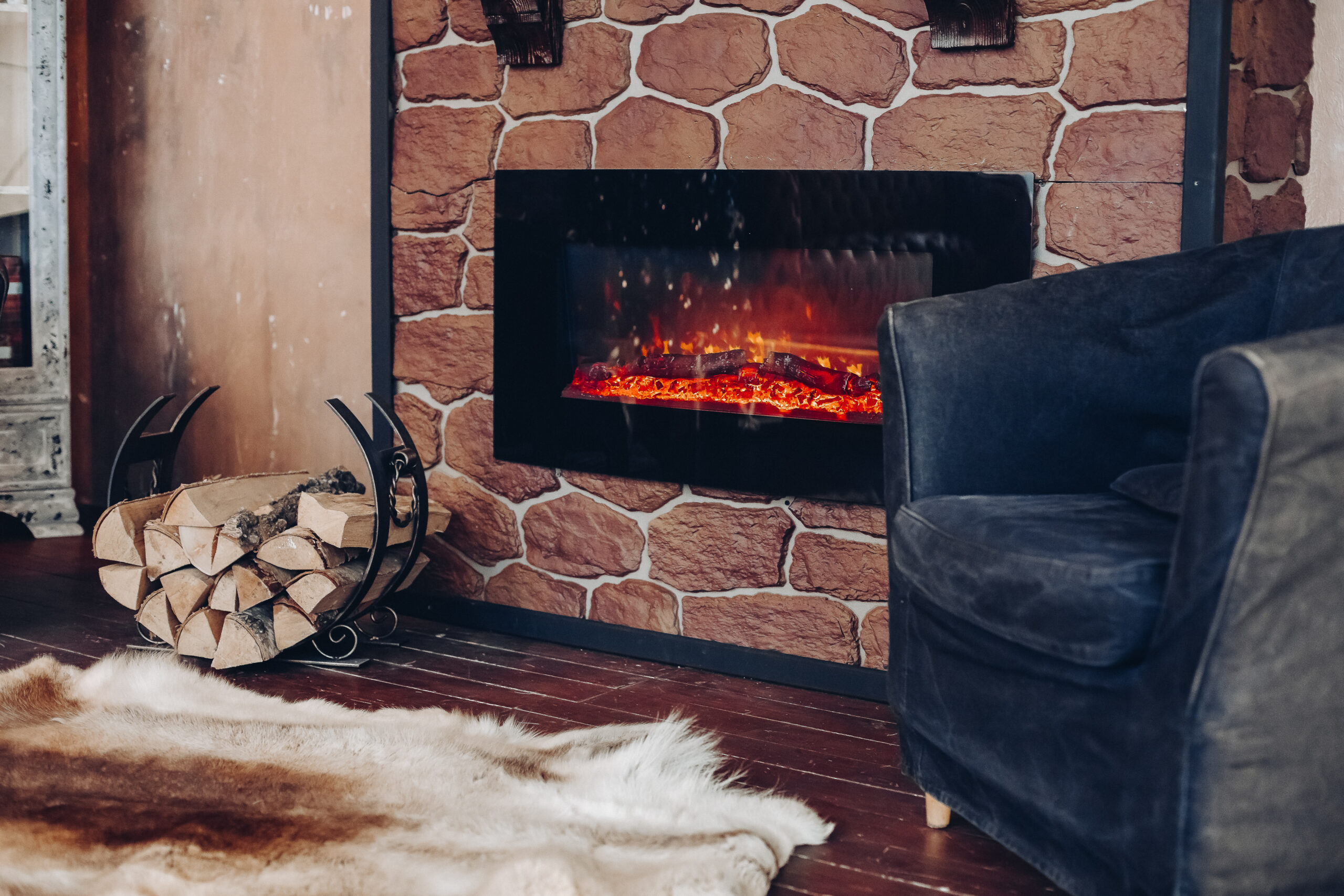 Cozy room with fireplace, fur skin and pile of woods.